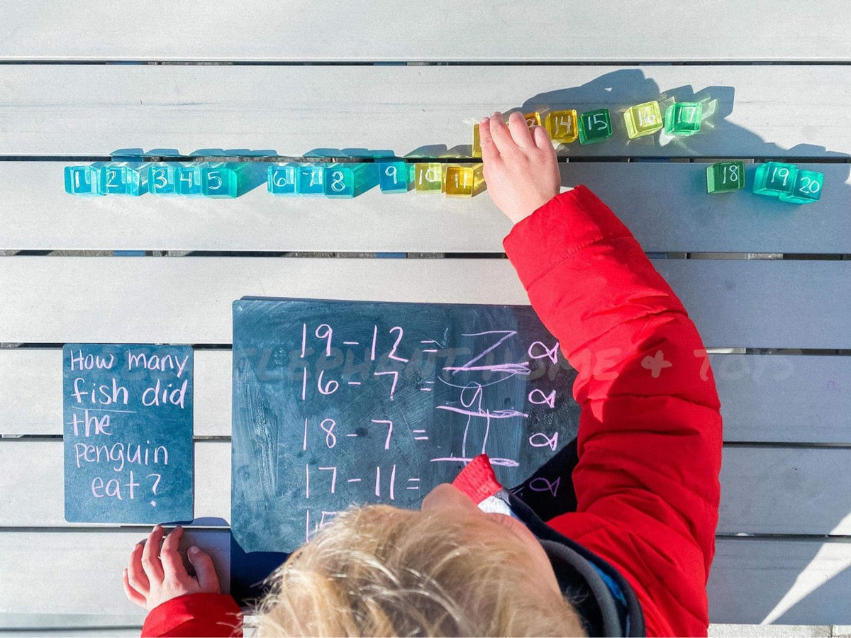 Child arranging numbered lucite cubes above a chalkboard during a math activity