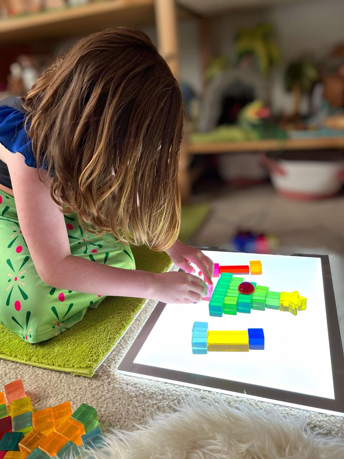 Child making colorful pictures with acrylic cubes on a light table; light table not included
