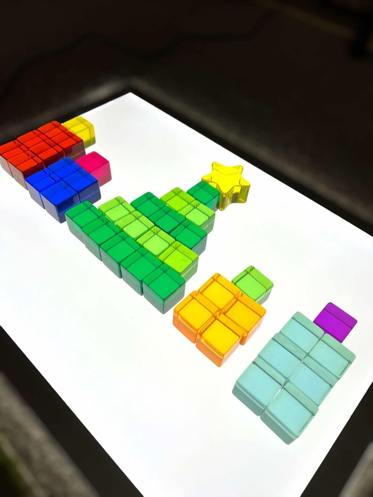 Rainbow lucite cubes arranged as a tree and gifts on a light table; accessories not included