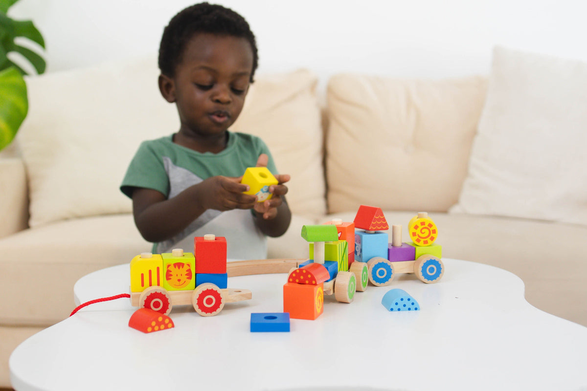 SpiritnSprout: Child arranging farm blocks on train cars at a table