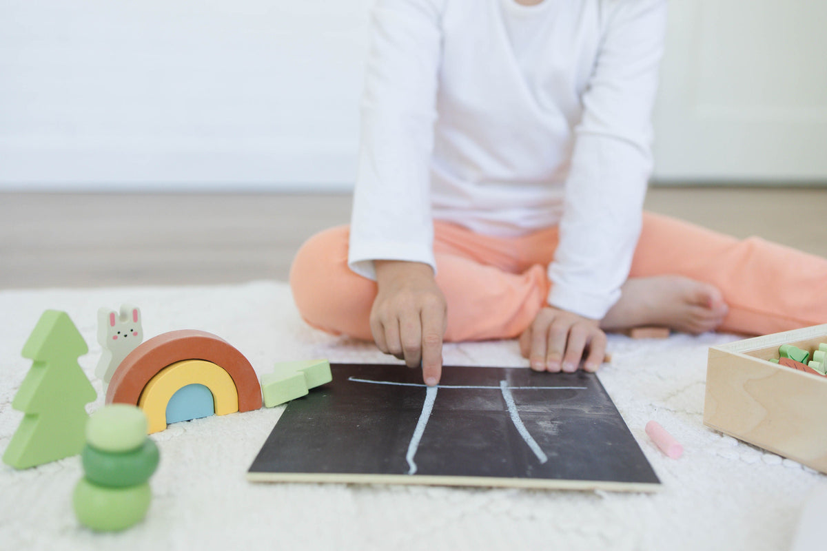 SpiritnSprout: Child drawing a woodland scene on the chalkboard lid