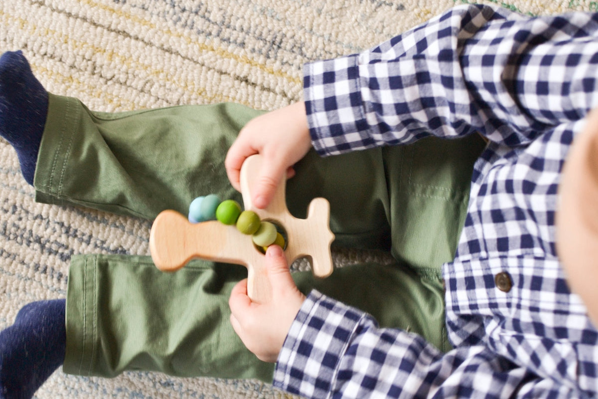 Lifestyle photo showing a wooden grasping toy with a child
