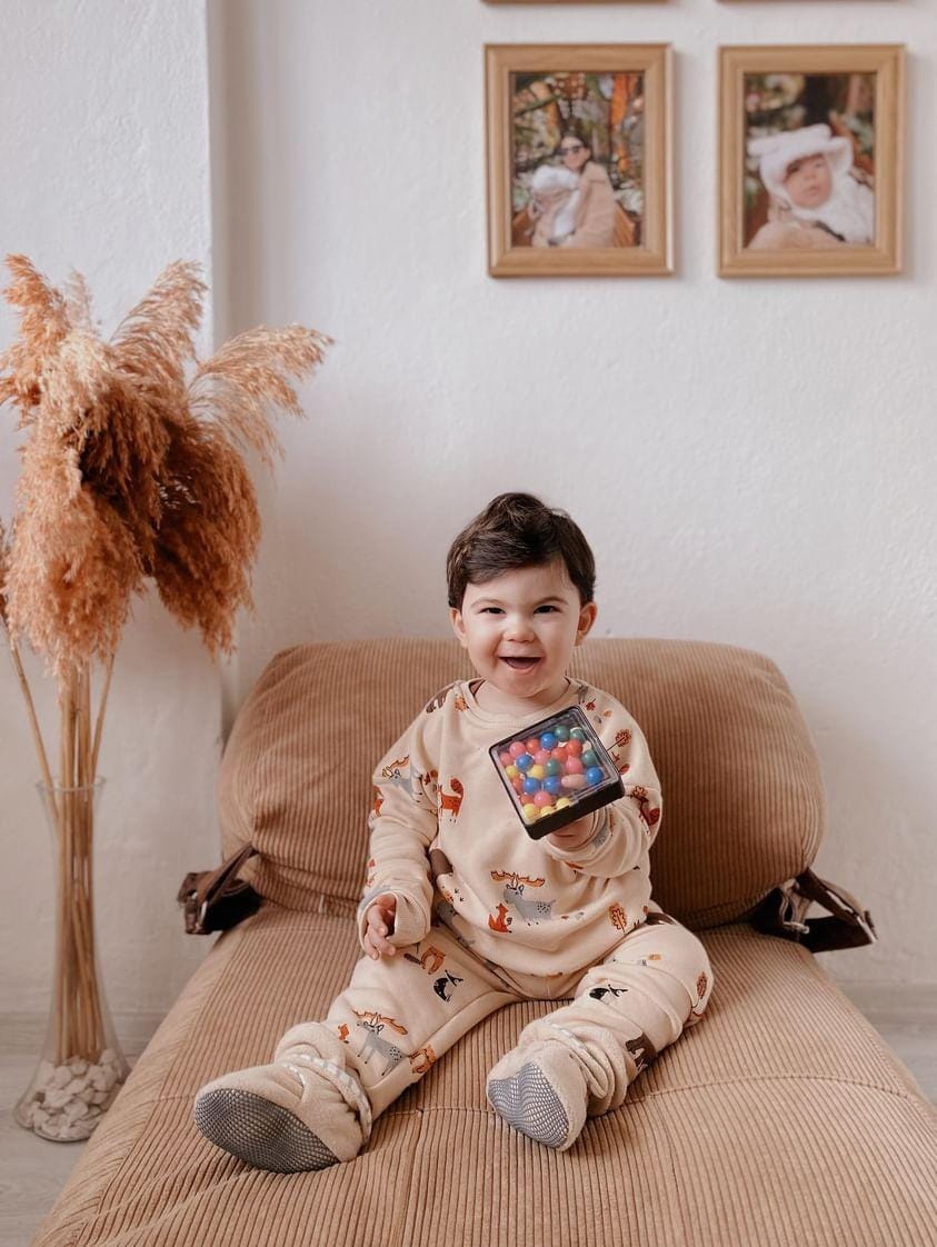 Child seated on a sofa wearing pajamas and pale gray footwear.