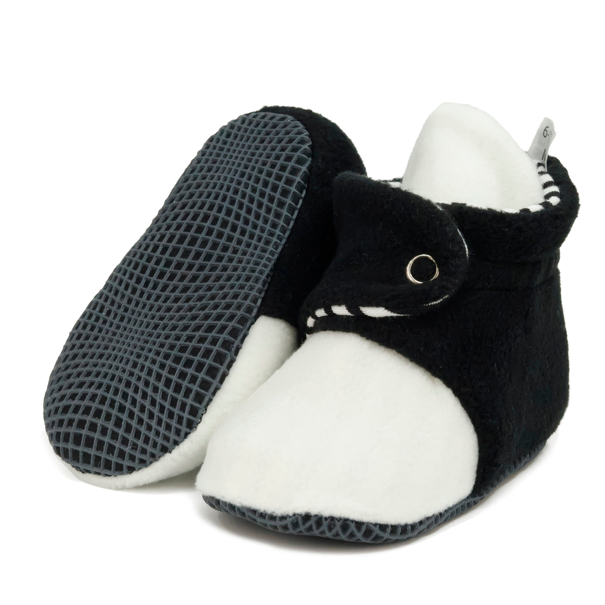 Black-and-white fleece baby booties with striped lining and snap straps, with one sole facing the camera on a white background.