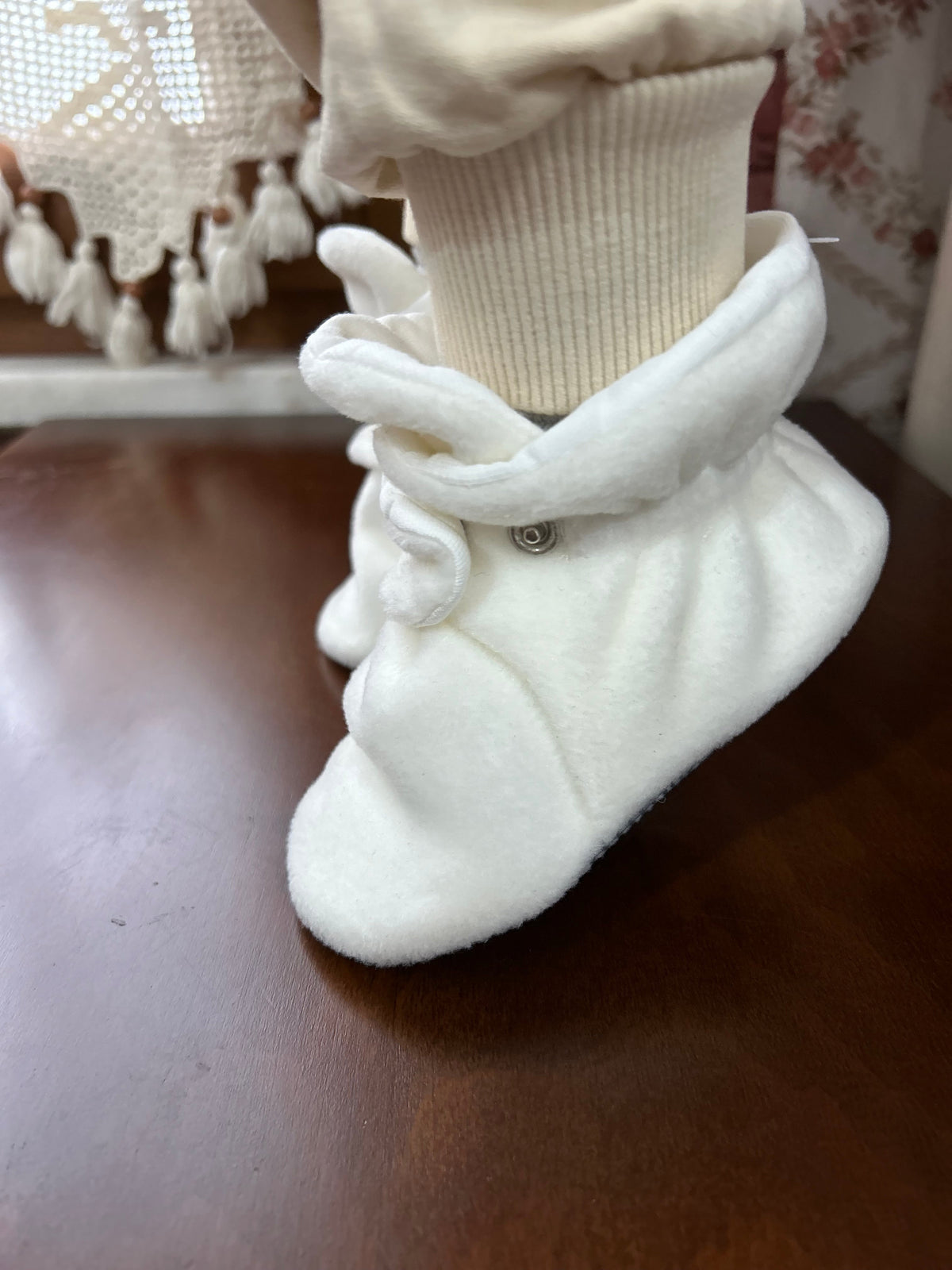 Side close-up of a white bootie worn with cream trousers.