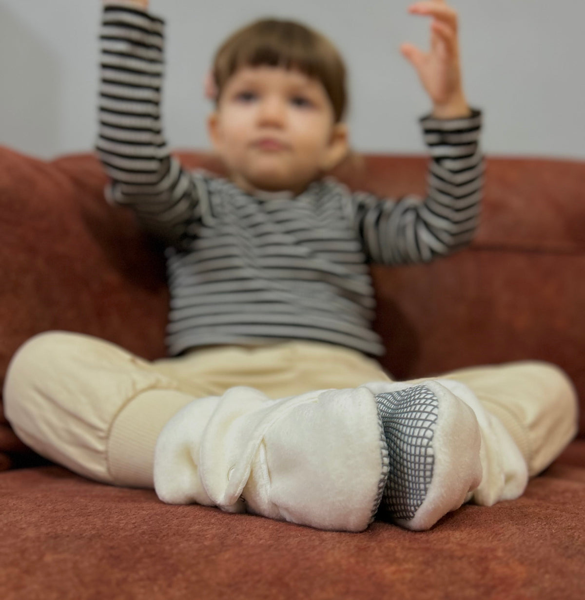 Child seated in a chair wearing white booties.