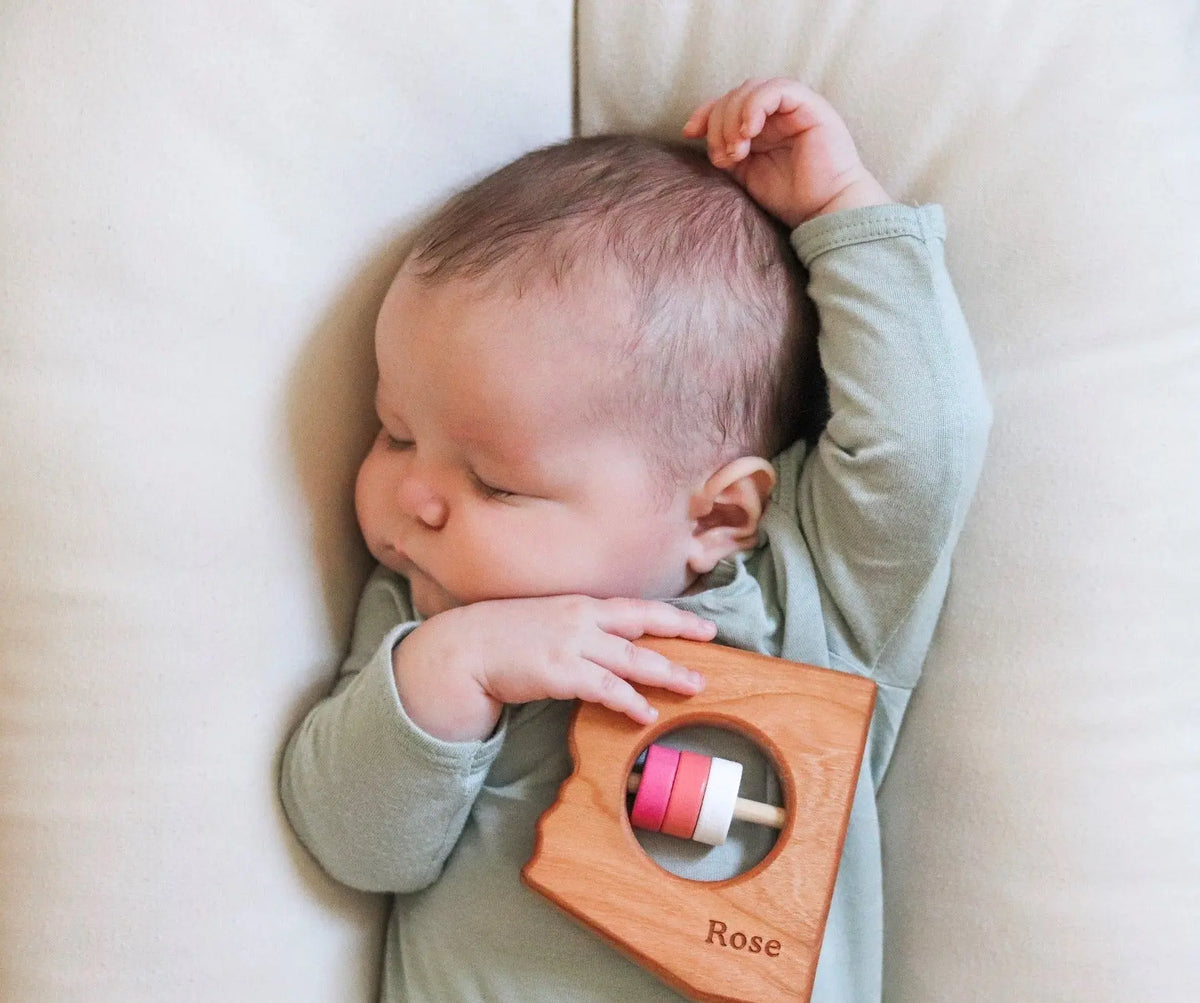 Lifestyle photo showing a wooden state rattle with a child