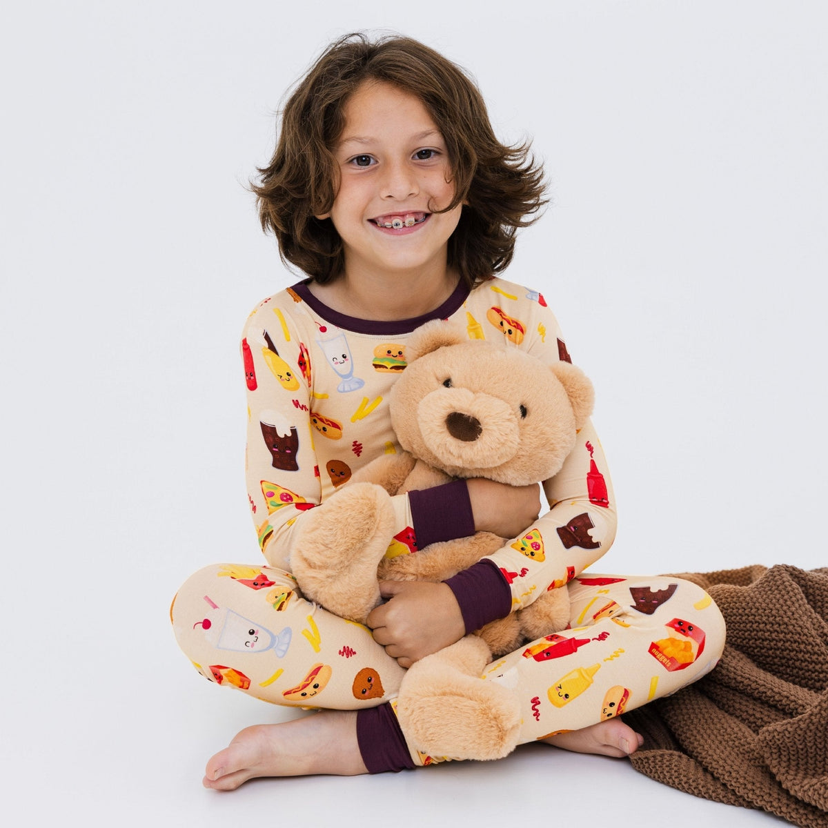 Child seated with a soft toy while wearing Bam & Stitch Blissful Bites Long Sleeve Pajamas.