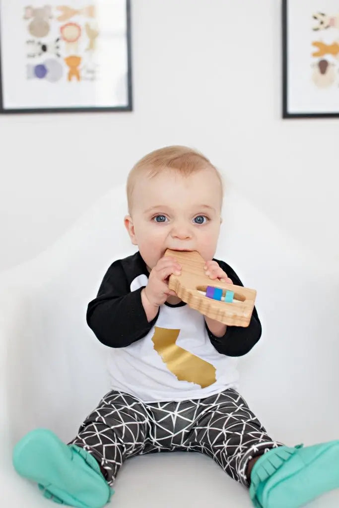 Lifestyle photo showing a wooden state rattle with a child