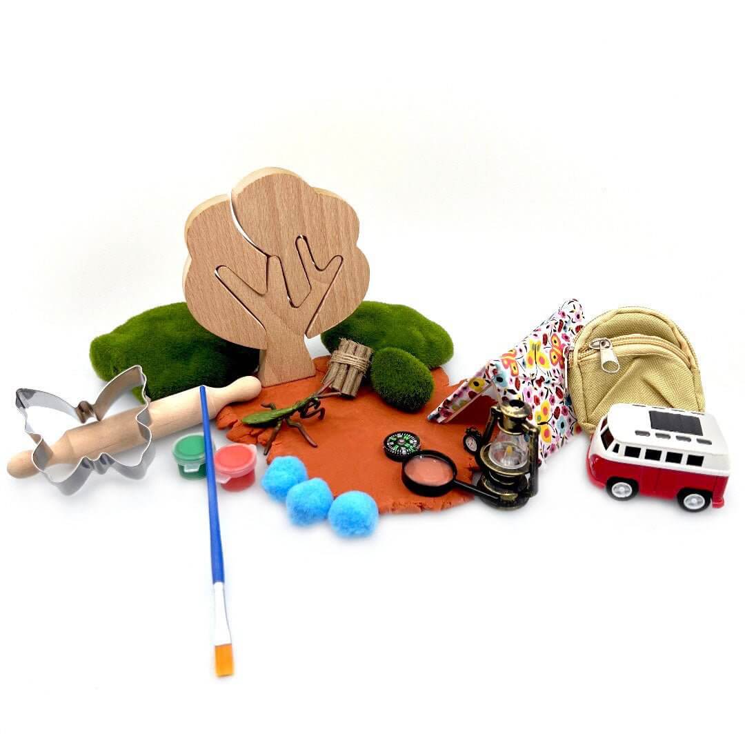 Camping Trip set arranged with orange playdough, camping miniatures, paint pots and tools
