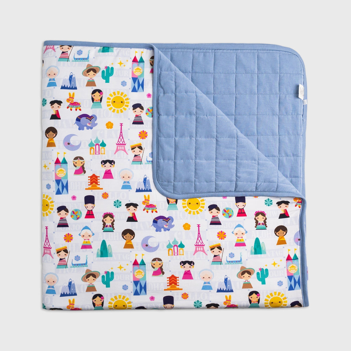 Bam & Stitch Children of the World Blanket laid flat with one corner turned back to show the quilted reverse.