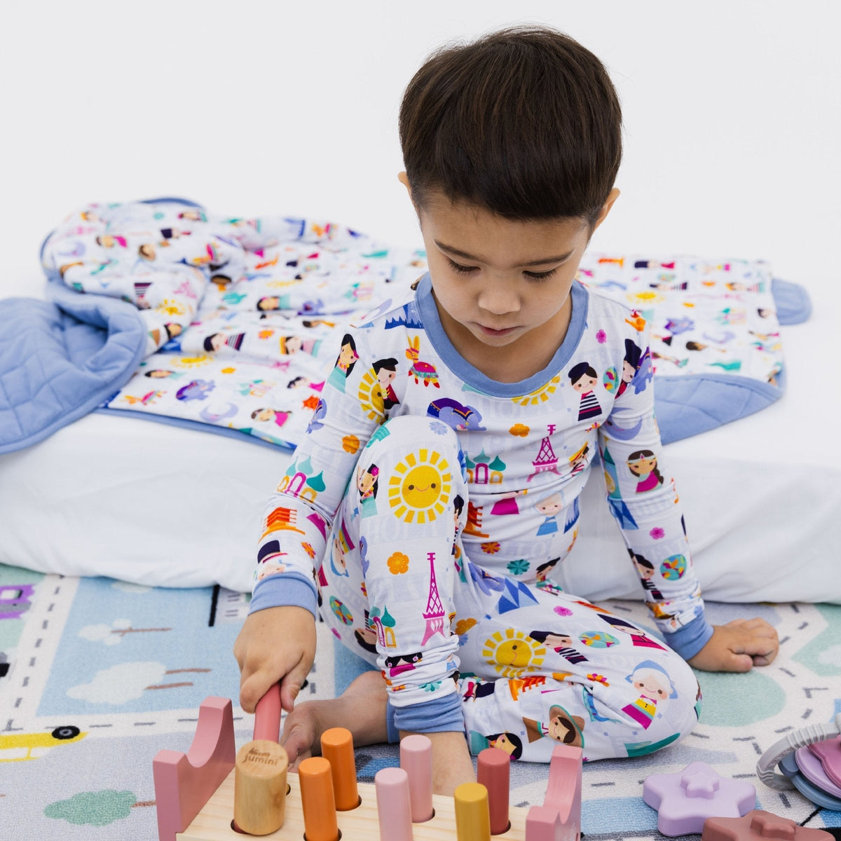 Child seated with toys while wearing Bam & Stitch Children of the World Long Sleeve Pajamas.