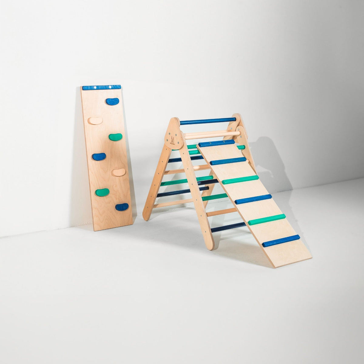 Blue and teal triangle with attached ladder ramp and a climbing-hold ramp beside it.