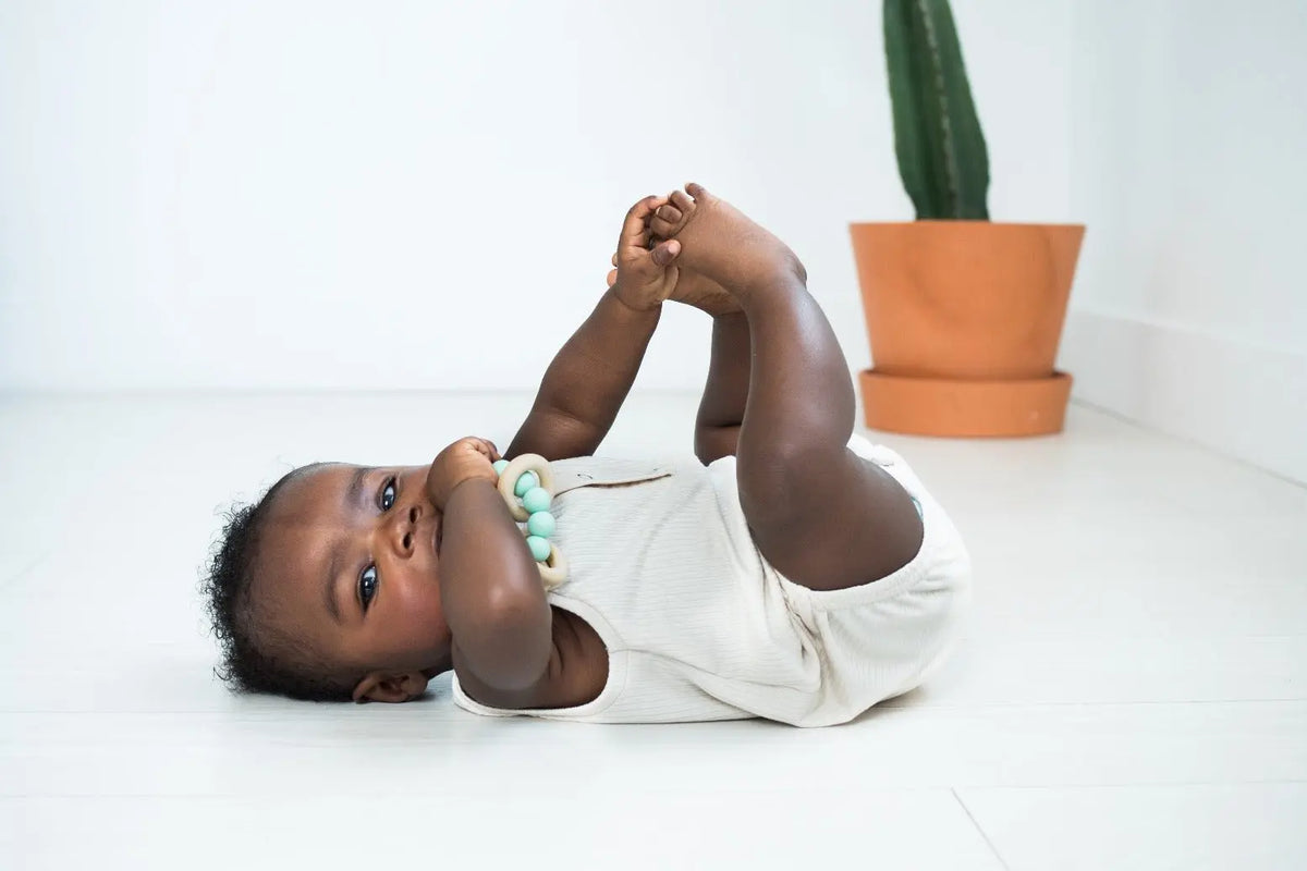 Lifestyle photo showing a wood and silicone teether with a child
