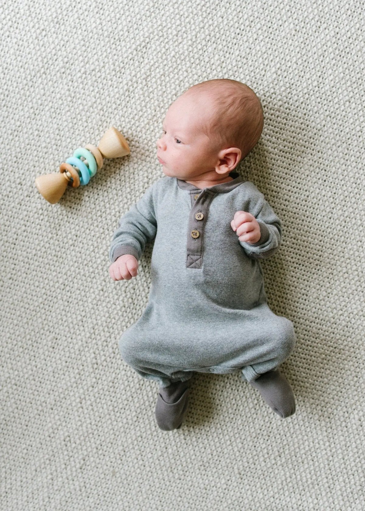 Lifestyle photo showing a wooden rattle with silicone rings with a child