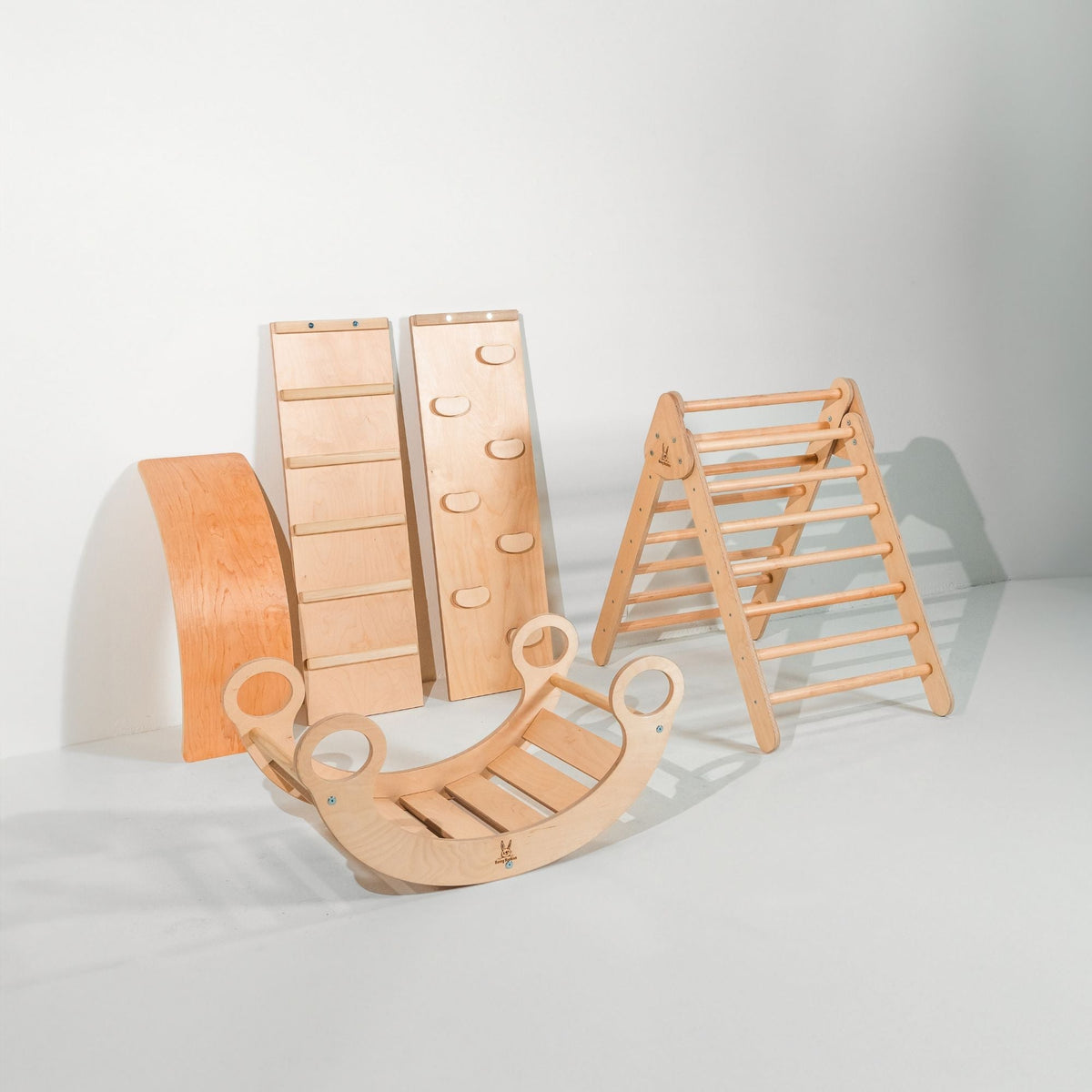Warm natural-tone climbing triangle, two ramps, curved wobble board and rocker displayed together.