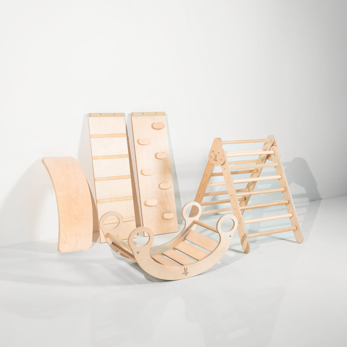 Pale natural-tone climbing triangle, two ramps, curved wobble board and rocker displayed together.