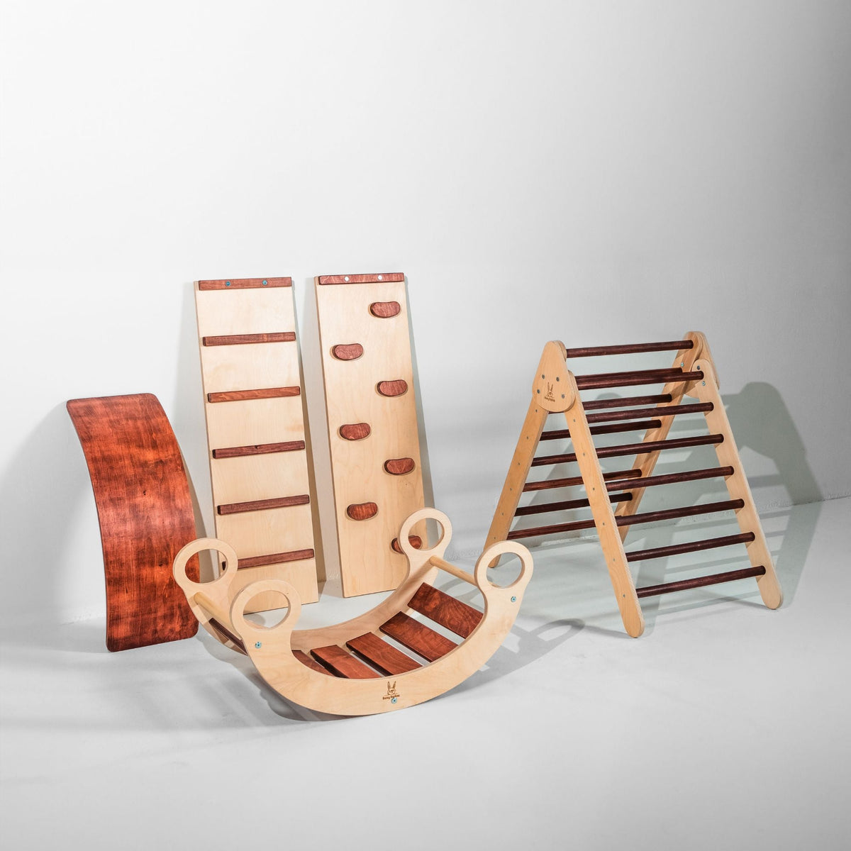 Reddish-brown climbing triangle, two ramps, curved wobble board and rocker displayed together.