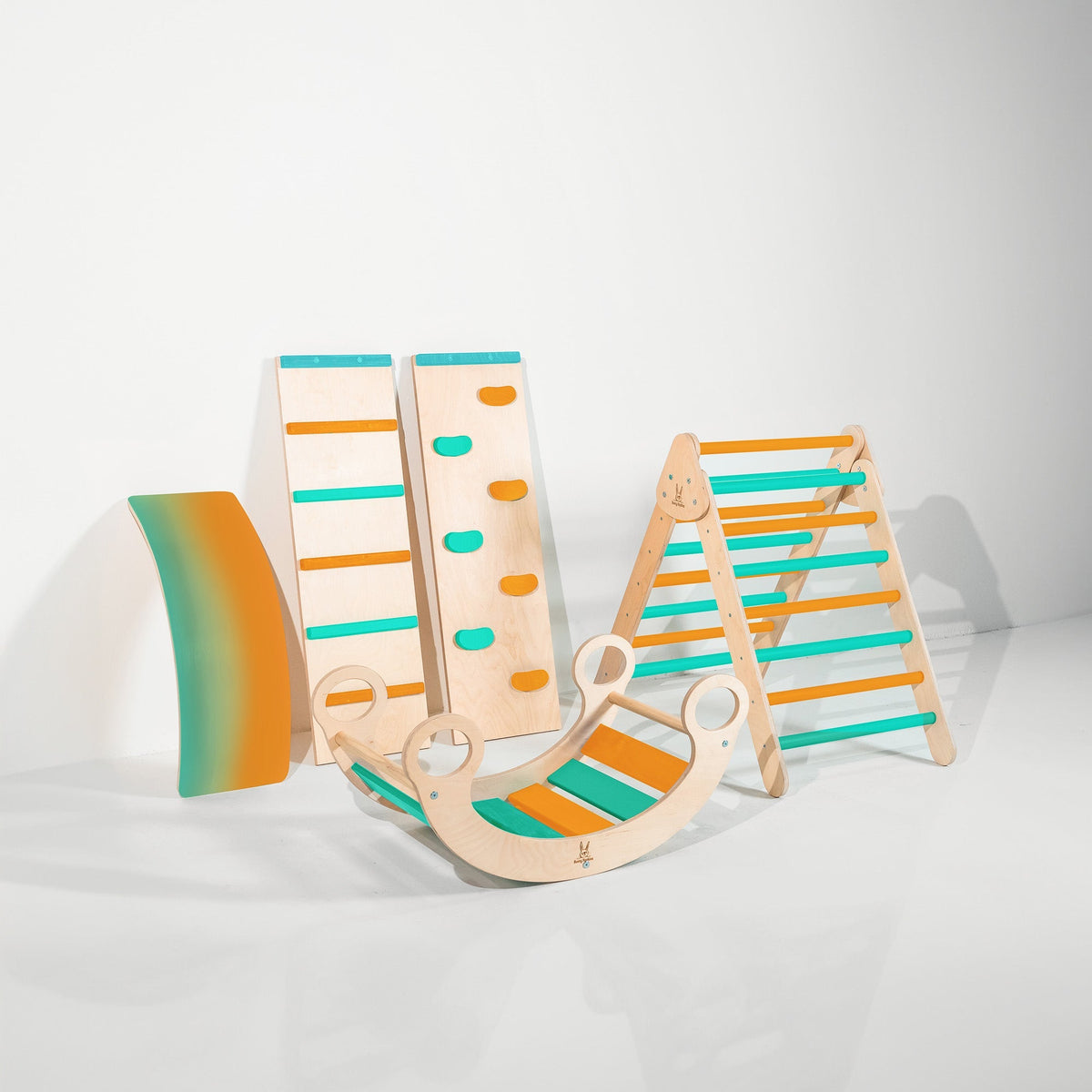 Teal and orange climbing triangle, two ramps, curved wobble board and rocker displayed together.