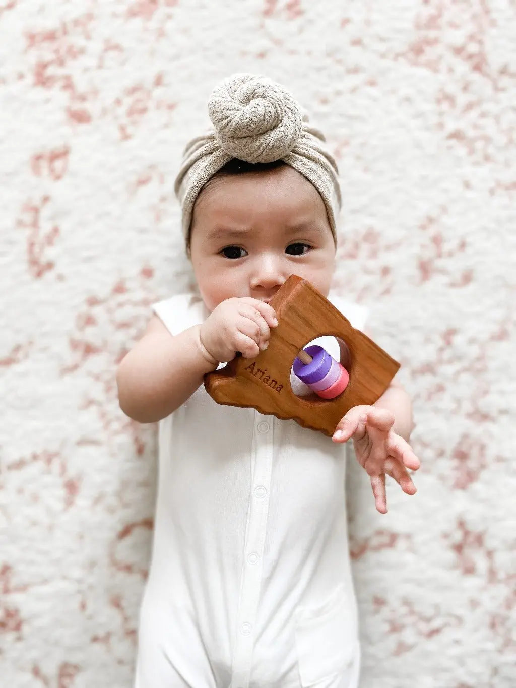 Lifestyle photo showing a wooden state rattle with a child