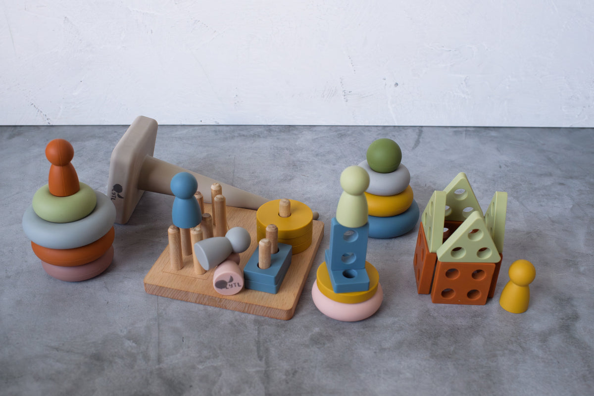 Peg dolls and puzzle shapes balanced on rings beside the wooden puzzle base.