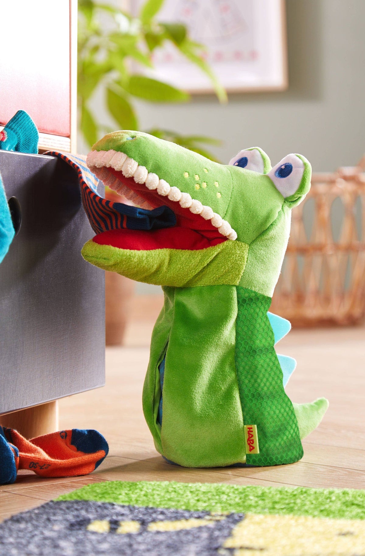 HABA Croco crocodile puppet with its mouth open beside a child