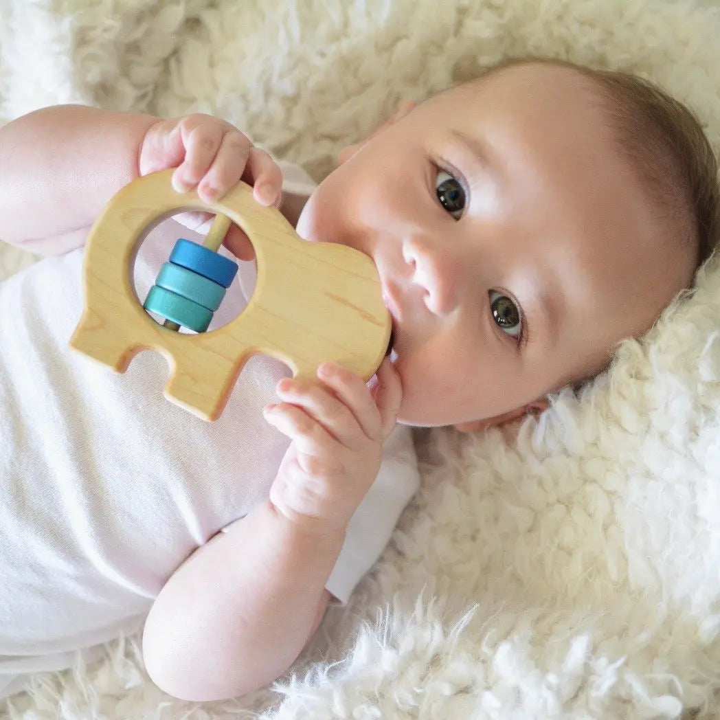 Lifestyle photo showing a wooden baby rattle with a child