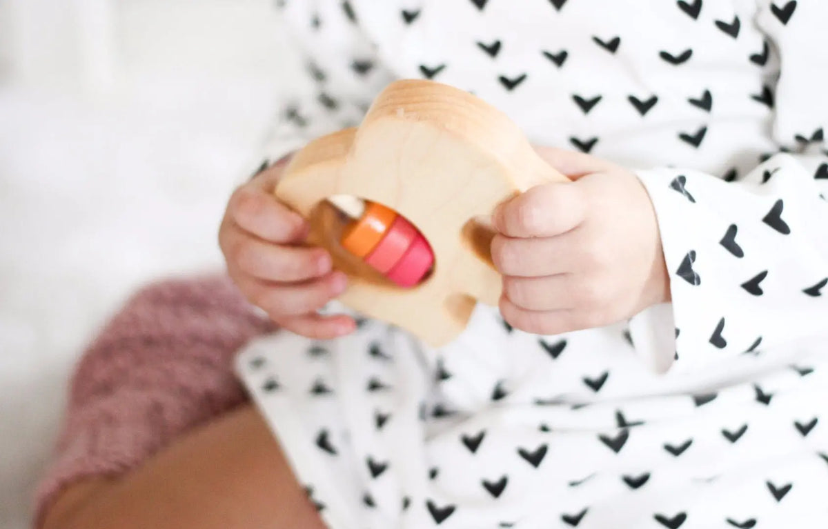 Lifestyle photo showing a wooden baby rattle with a child