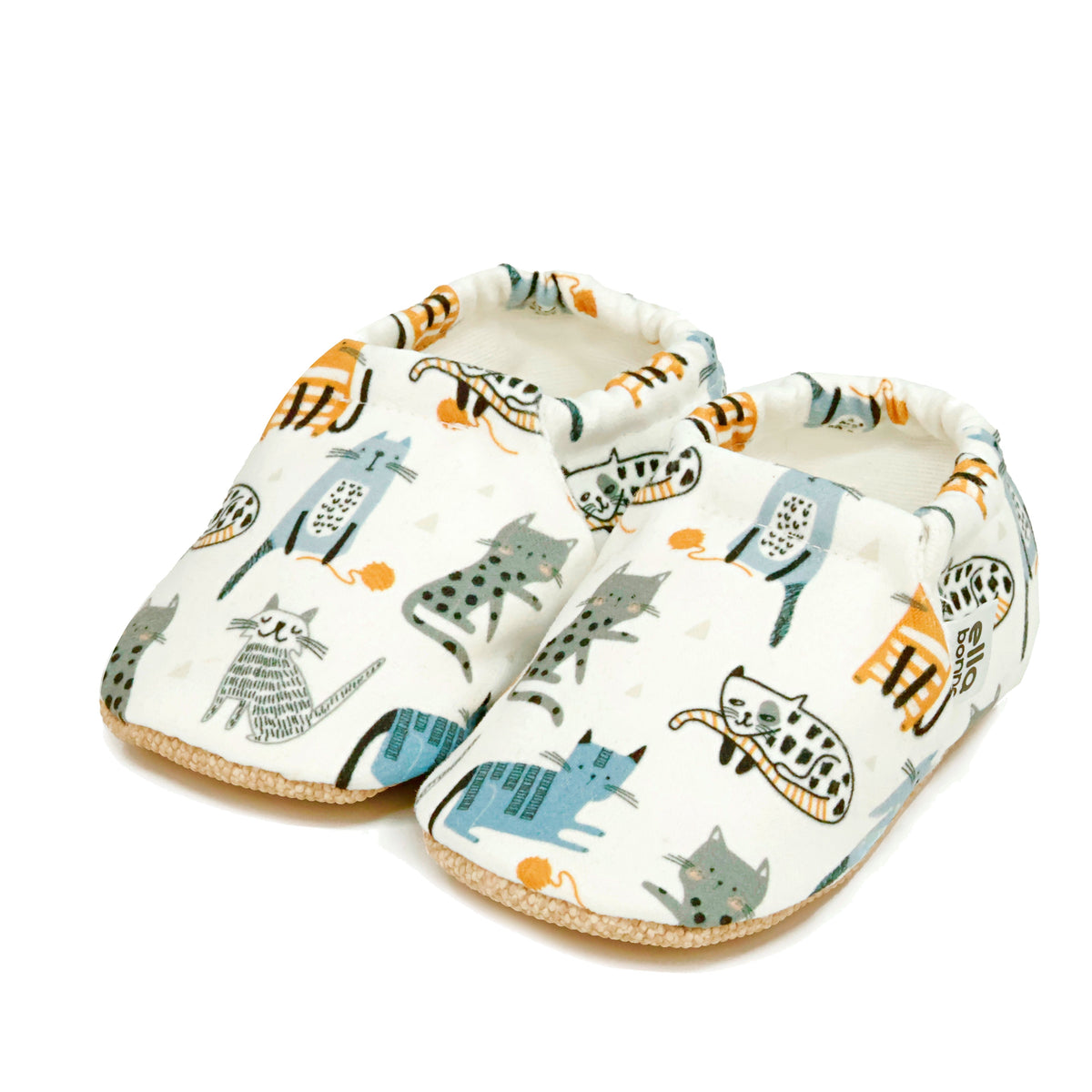 Pair of cream slip-on baby moccasins with illustrated cat print on a white background.