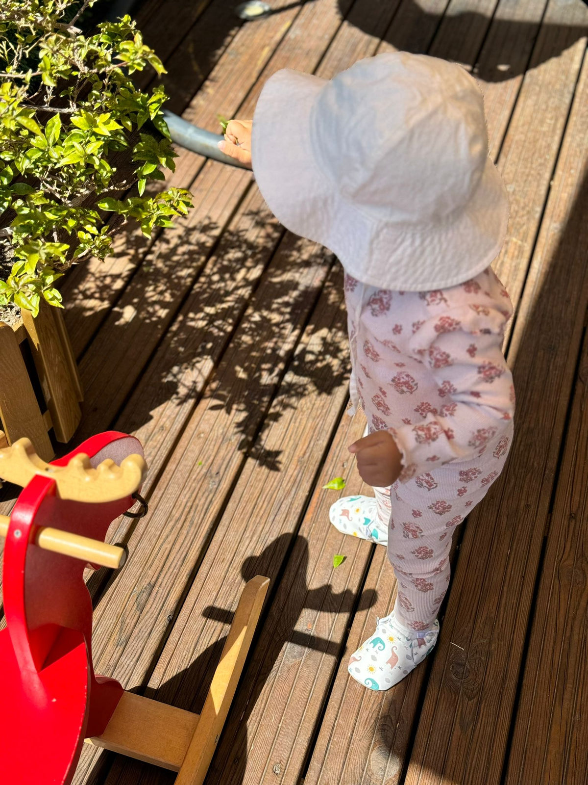 Side view of a child standing on a deck wearing elephant-print moccasins.