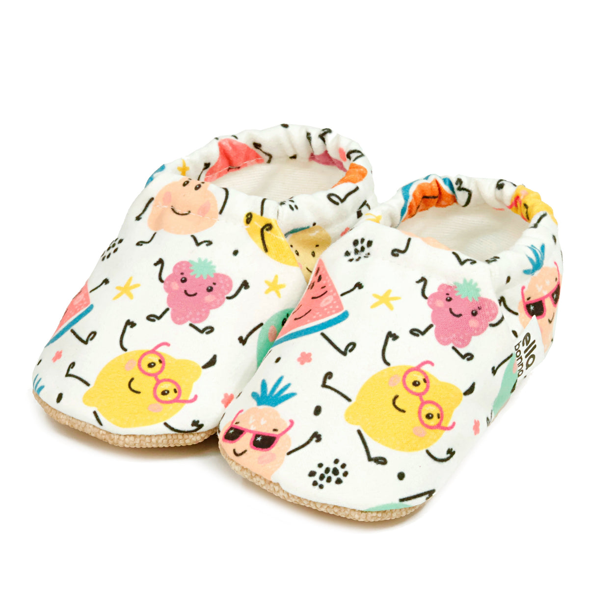 Pair of cream slip-on baby moccasins with colorful smiling fruit print on a white background.
