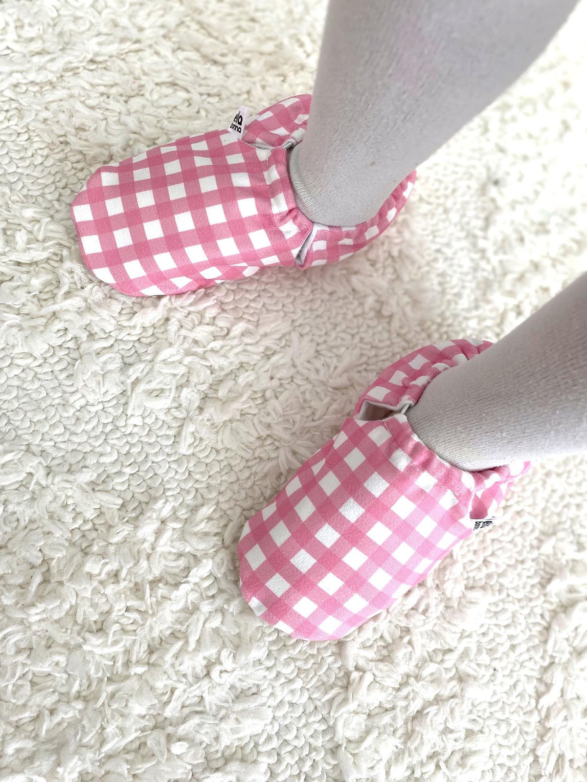 Overhead close-up of pink gingham moccasins worn with white tights.