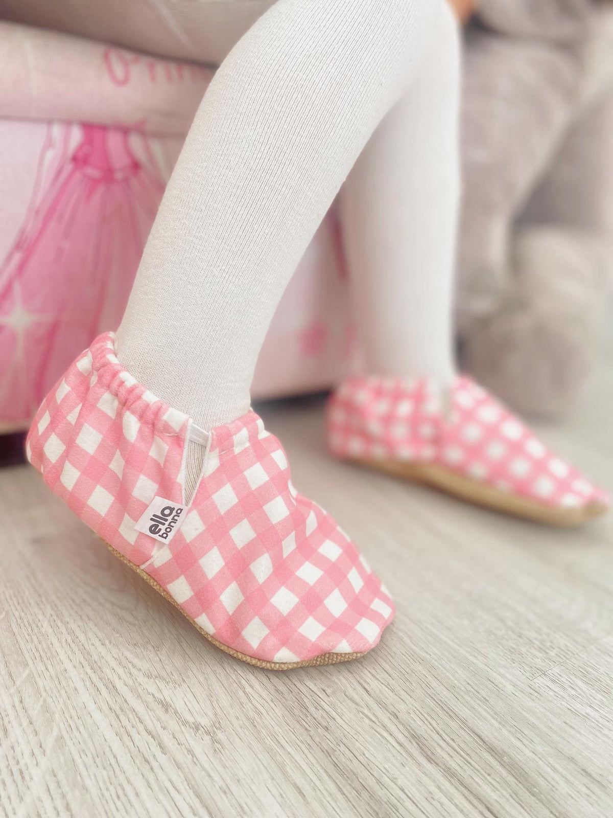 Close-up of pink gingham moccasins worn while seated.
