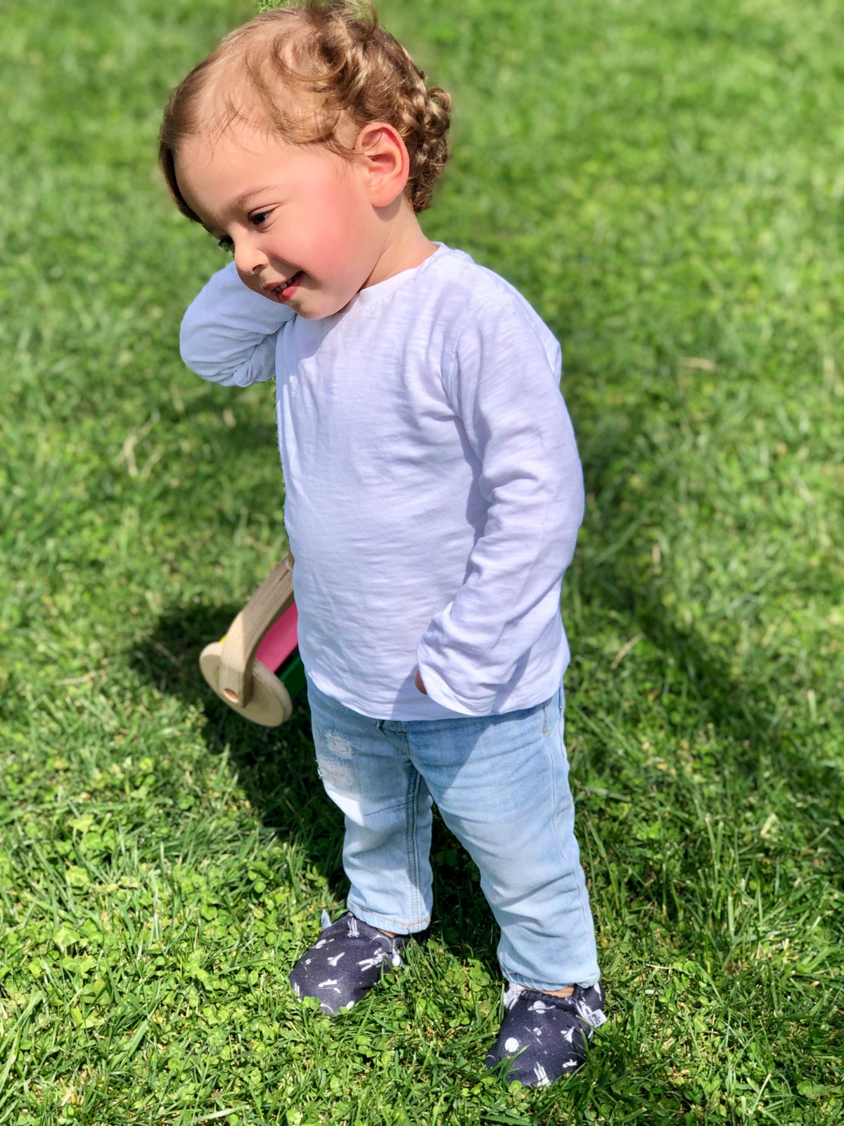 Child standing on grass wearing dark moccasins.