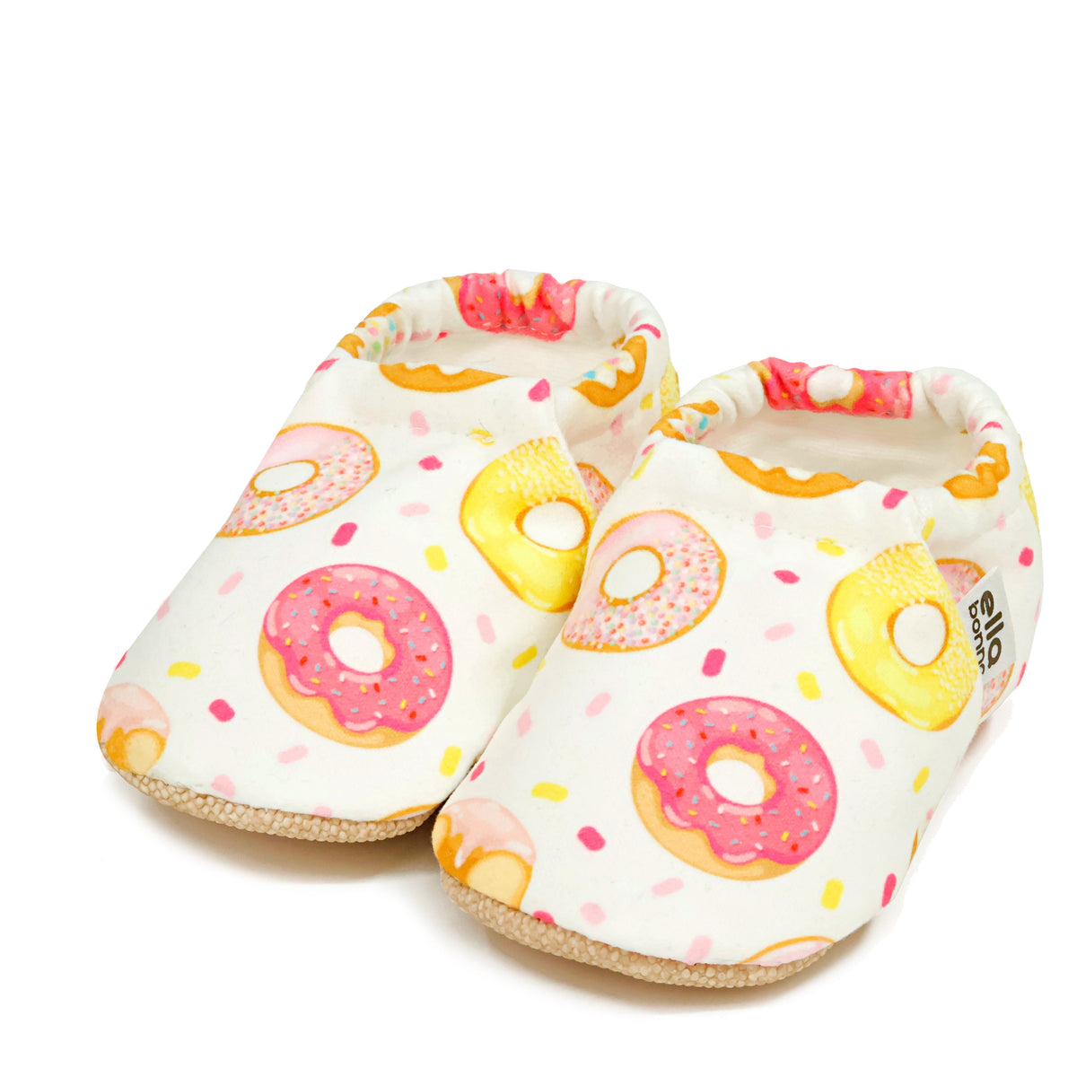 Pair of cream slip-on baby moccasins with pink-and-yellow doughnut print on a white background.