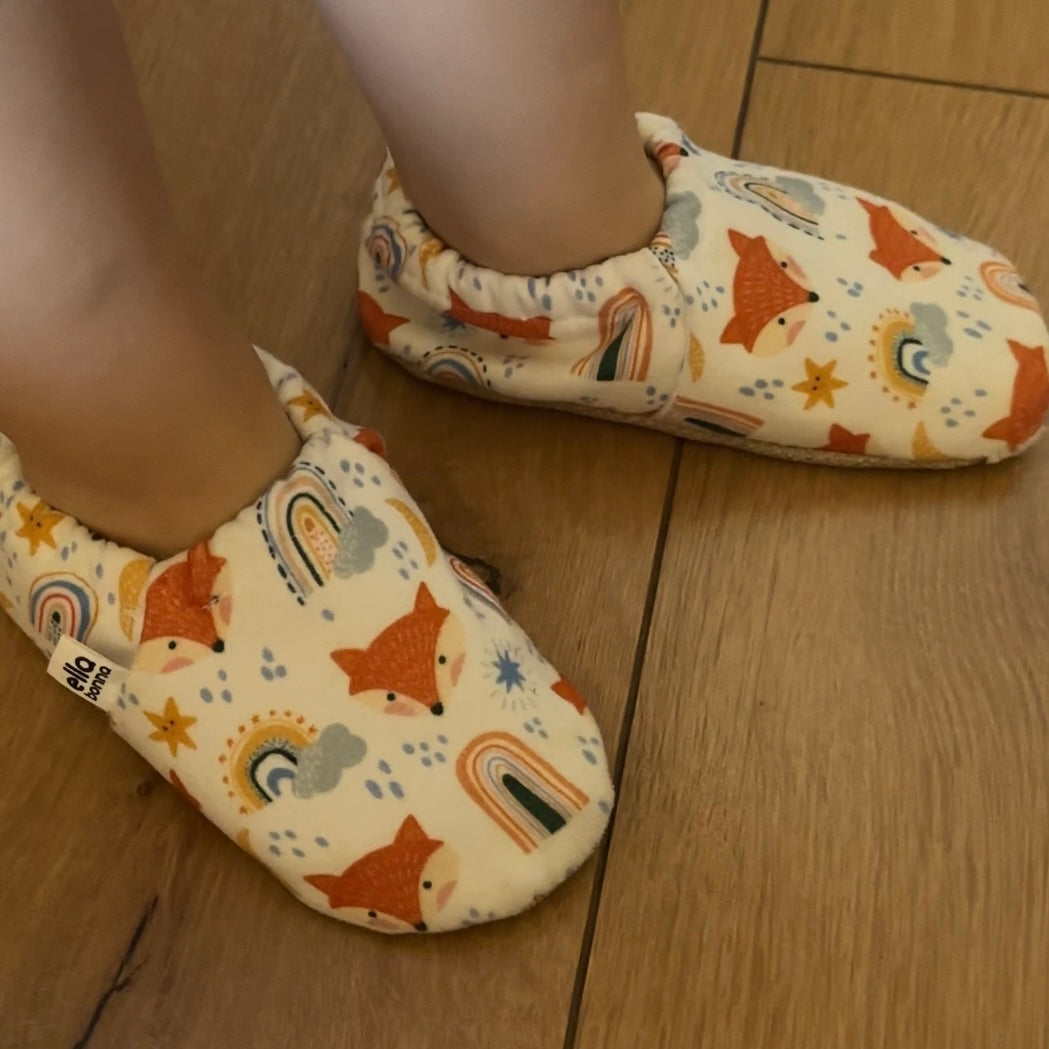Close-up of fox-print moccasins worn while standing on a wooden floor.