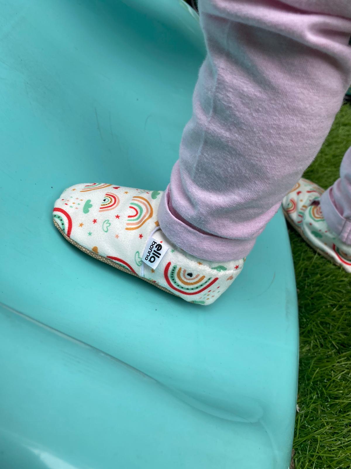 Close-up of a rainbow-print moccasin worn on a turquoise slide.
