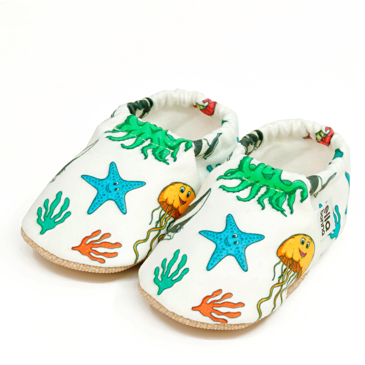 Pair of cream slip-on baby moccasins with colorful sea animals and starfish on a white background.