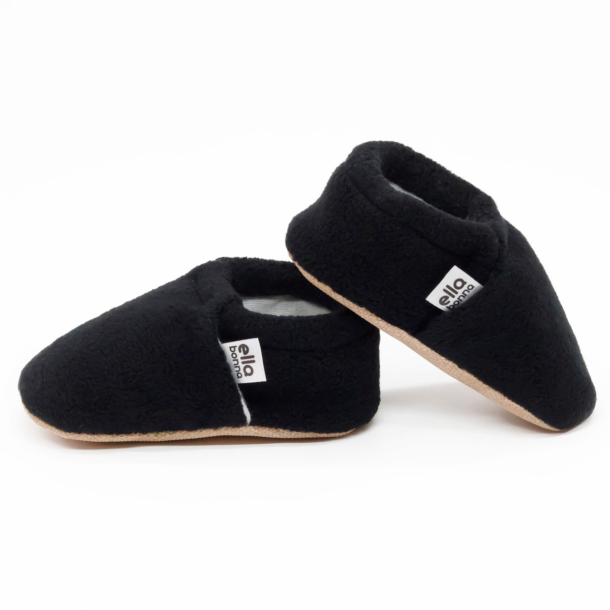 Side views of black fleece slip-on baby moccasins with tan soles on a white background.