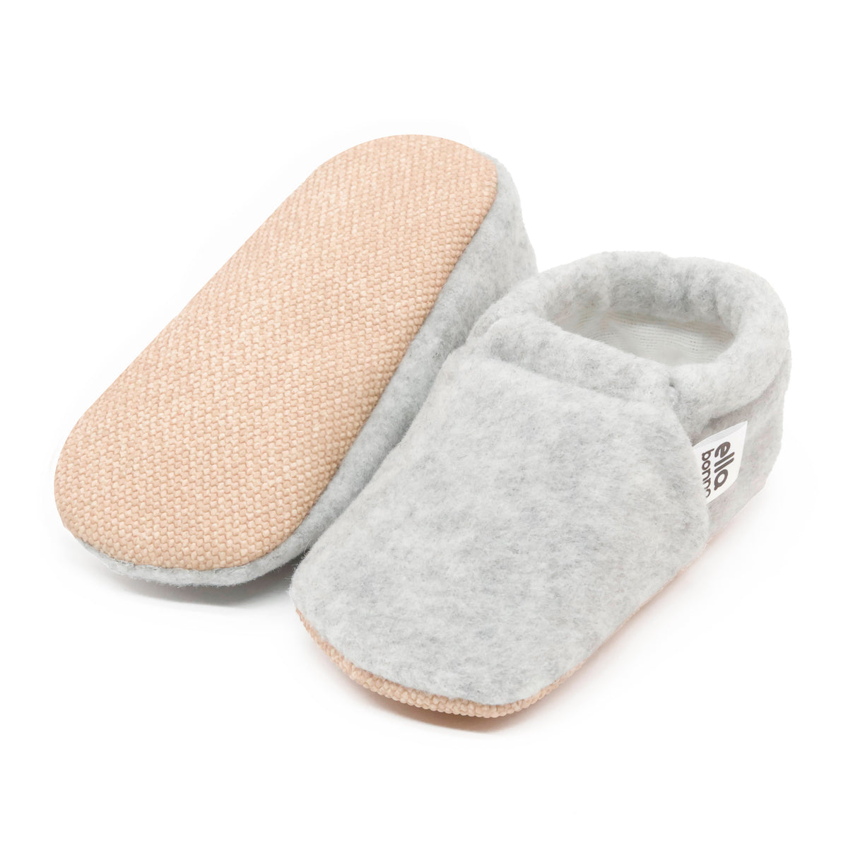 Light gray fleece slip-on baby moccasins with tan soles, with one sole facing the camera on a white background.