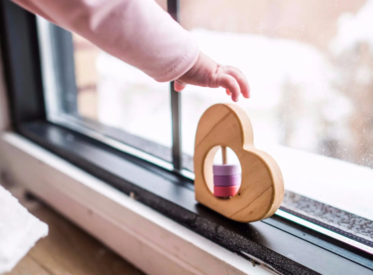 Lifestyle photo showing a wooden baby rattle with a child