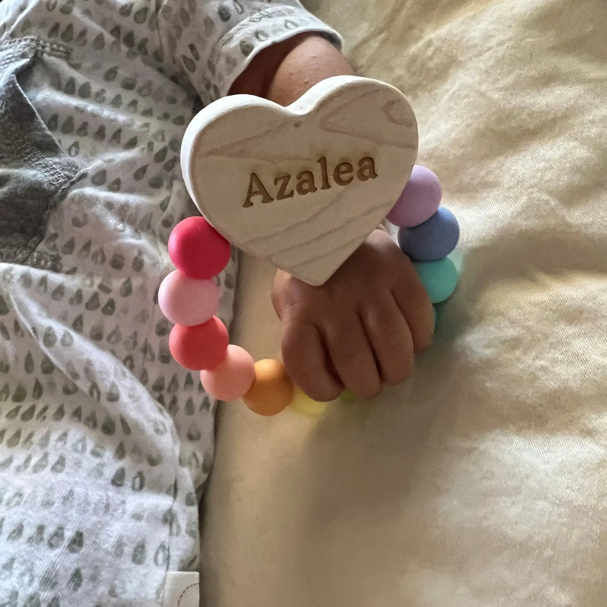 Lifestyle photo showing a wood and silicone teether with a child