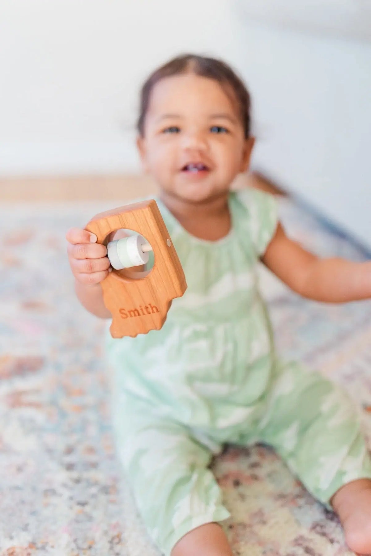 Lifestyle photo showing a wooden state rattle with a child