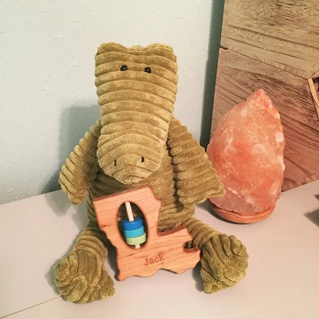 Louisiana-shaped wooden rattle displayed with a stuffed alligator