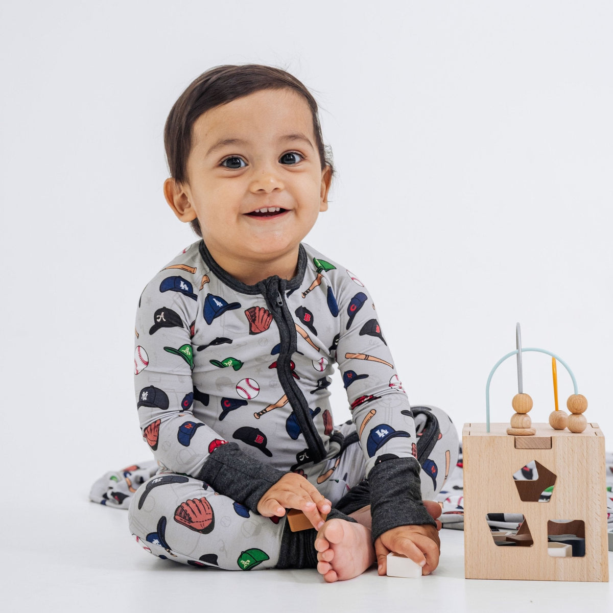 Baby seated beside a wooden activity cube in Bam & Stitch Major League Buddies Convertible Romper.