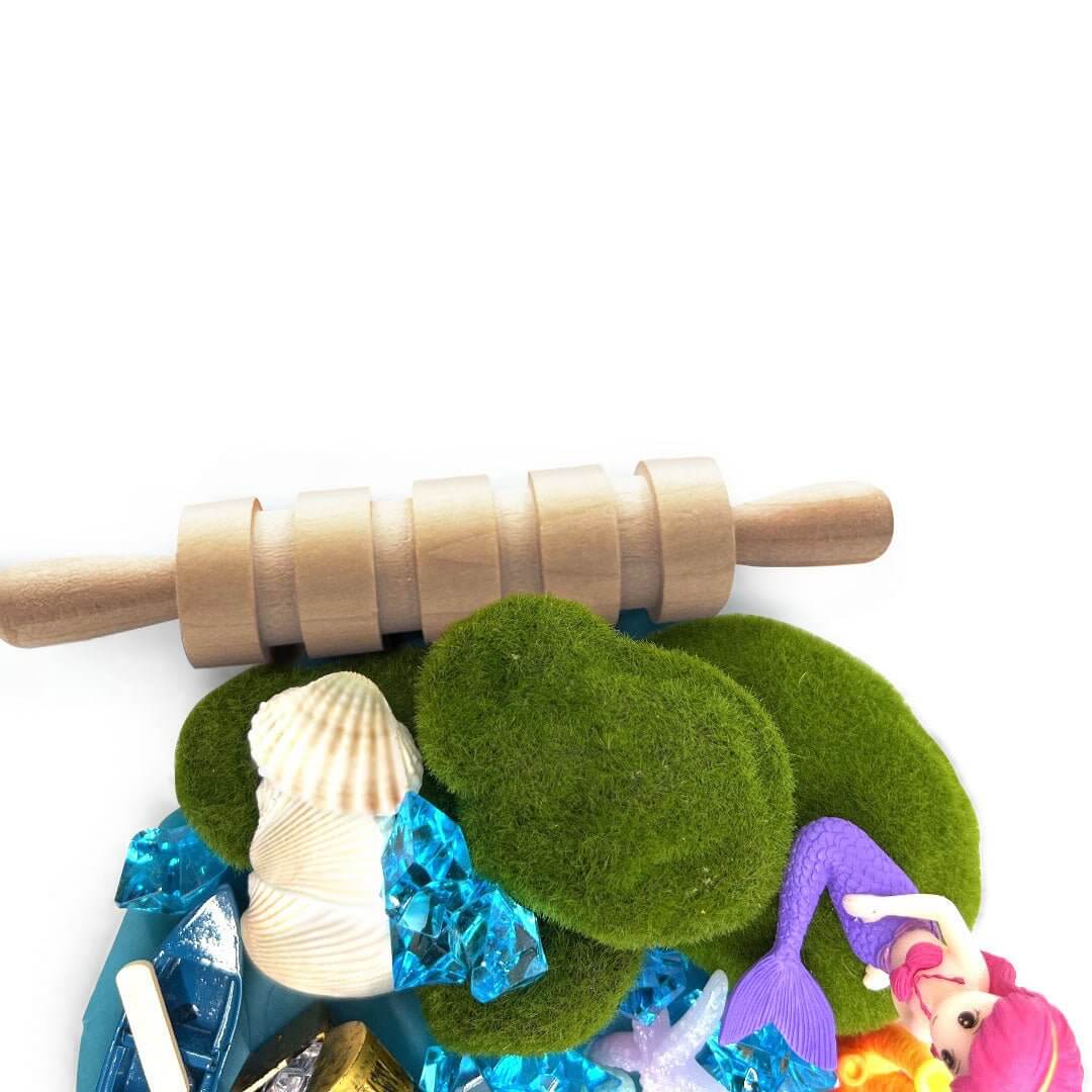 Grooved rolling pin above shells, green decorations and mermaid accessories