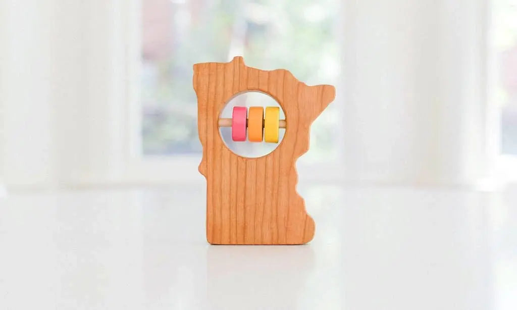 Bannor Toys Minnesota Wooden Baby Rattle, showing state-shaped cherry-wood body and colored rattle discs
