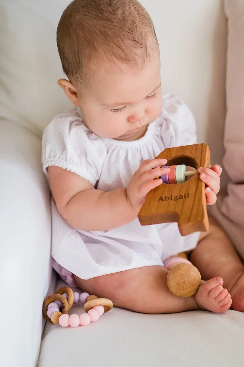 Lifestyle photo showing a wooden state rattle with a child