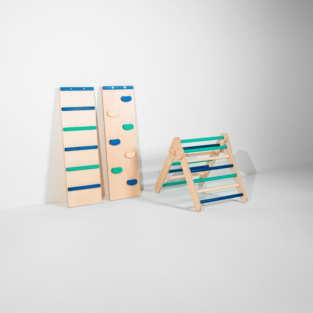 Small blue, teal and natural-tone climbing triangle beside two upright ramps.