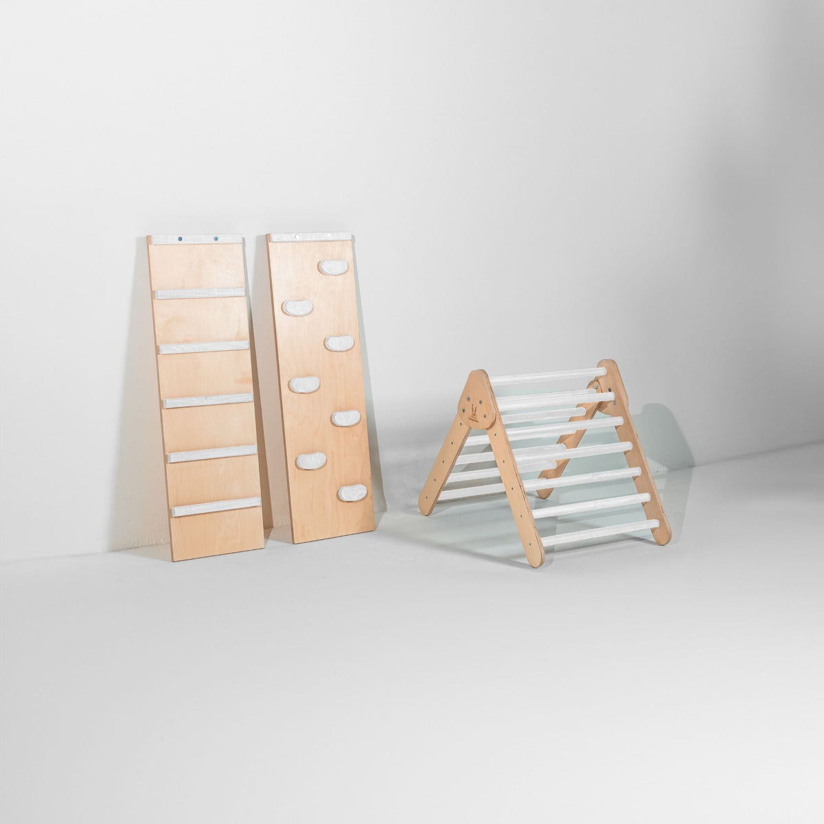 Small white-rung climbing triangle beside upright ladder and white-hold climbing ramps.
